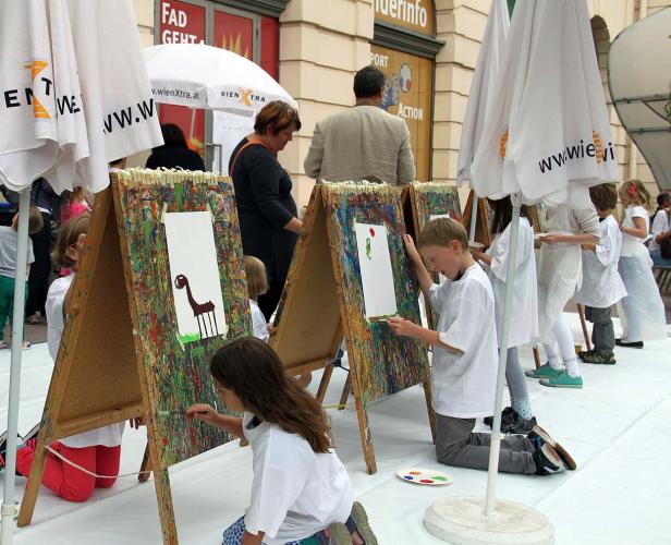 Kinder malen auf Staffeleien im Freien.