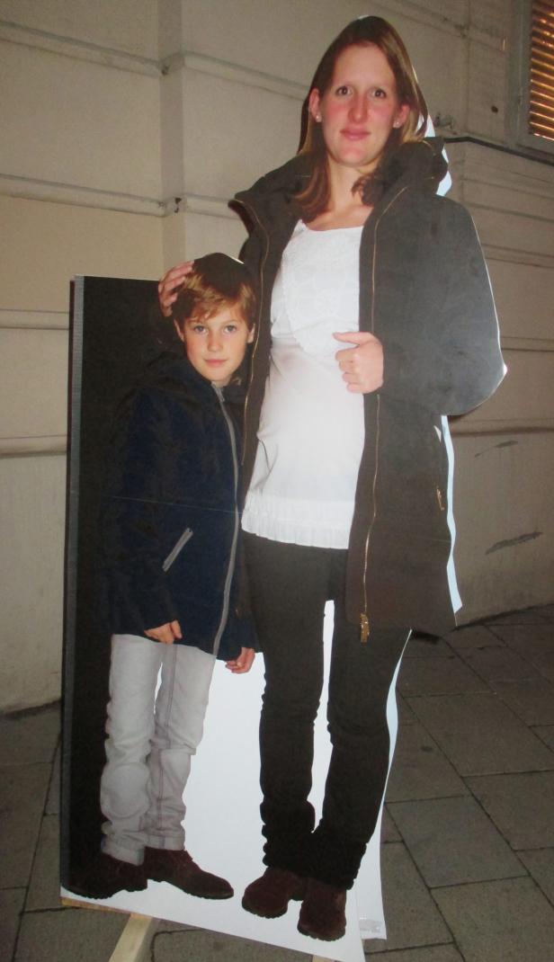 Eine Frau posiert neben einem Pappaufsteller eines Jungen.