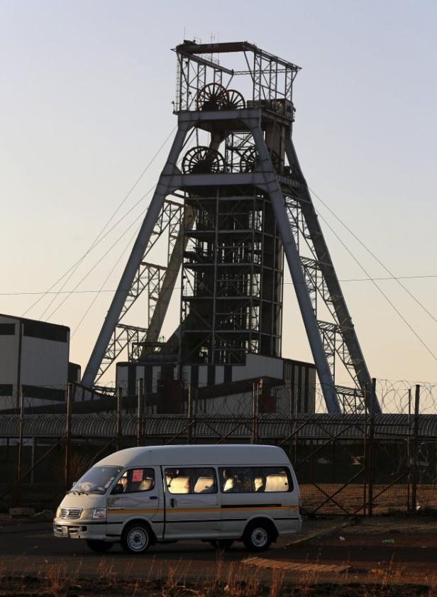 Ein Minibus steht vor einem Förderturm einer Mine.