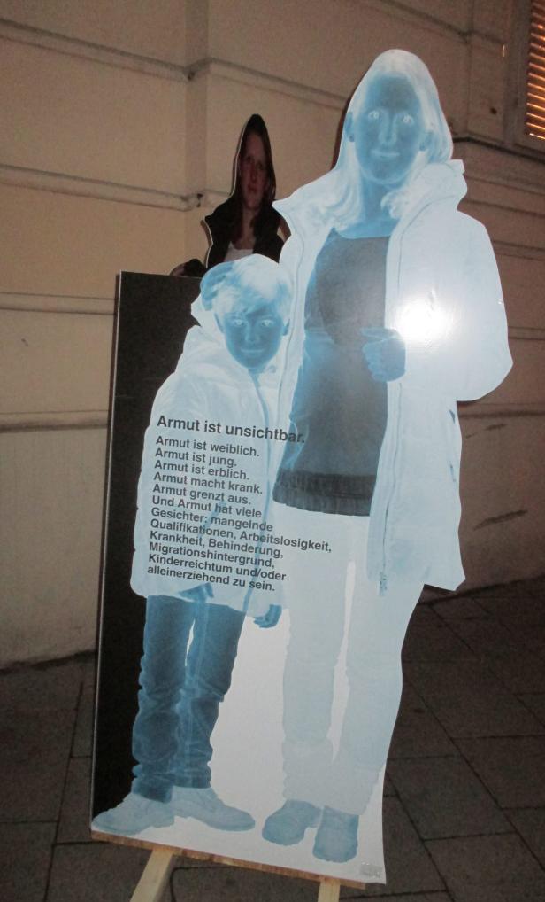 Eine Ausstellung zeigt stilisierte Figuren und Text über Armut.