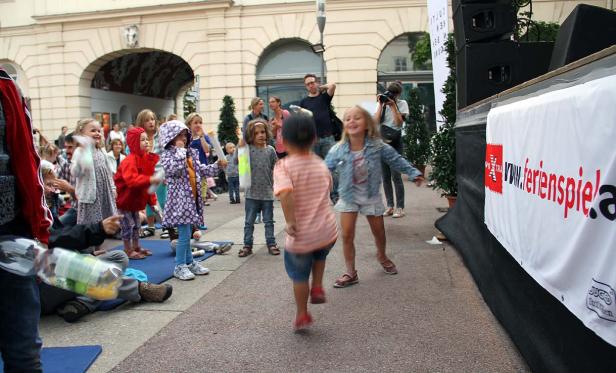 Eine Gruppe Kinder tanzt auf einer Bühne bei einer Veranstaltung von ferienspiele.at.