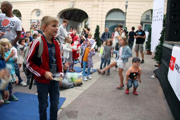 Eine Gruppe von Kindern spielt und tanzt auf einer Straße.