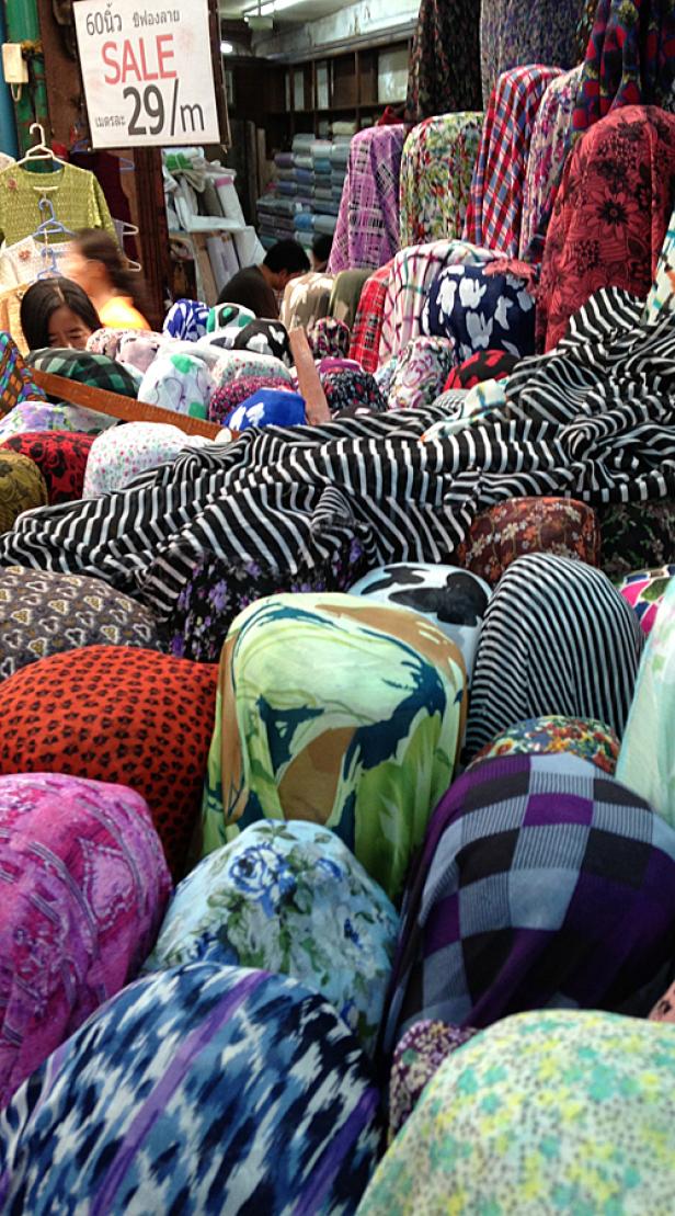 Eine Auswahl an bunten Stoffen in einem Geschäft, mit einem Schild, das einen Sonderpreis anzeigt.