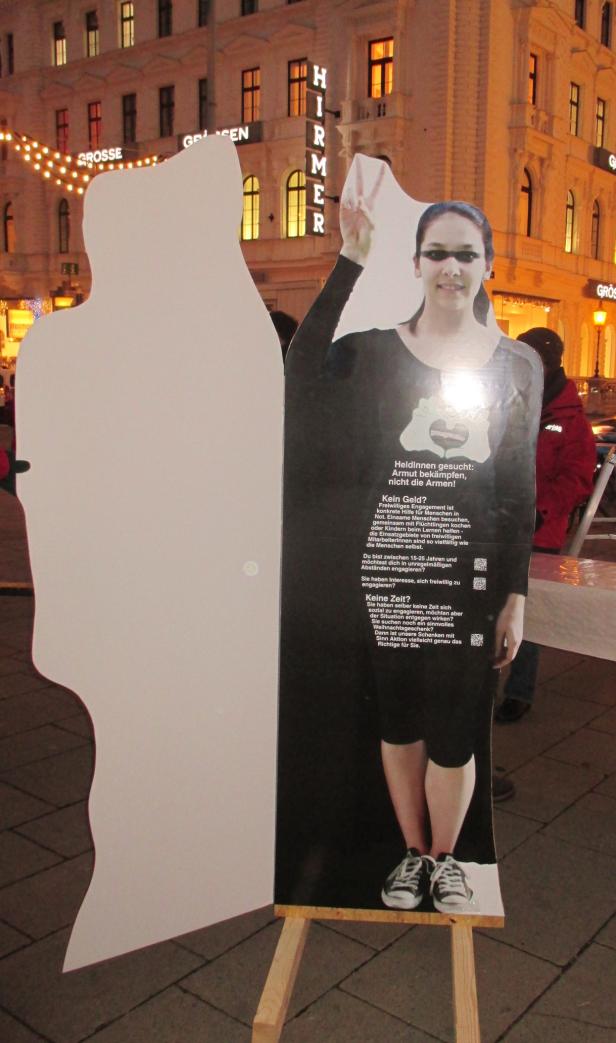 Eine Frau posiert neben einer Pappfigur für eine Kampagne gegen Armut in Wien.