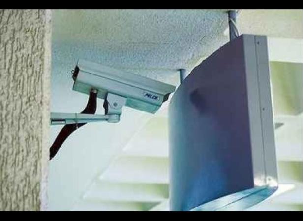 Eine Überwachungskamera ist an einer Wand neben einem Monitor montiert.