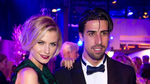 Eine Frau in einem grünen Kleid und ein Mann mit Fliege posieren für ein Foto.