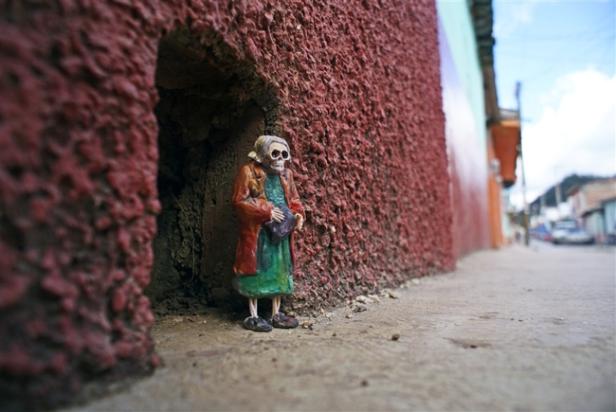 Eine Miniatur-Skelettfigur steht in einer Mauernische auf einem Bürgersteig.