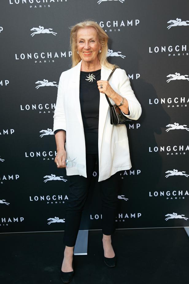 Eine Frau posiert vor einer Longchamp-Fotowand.