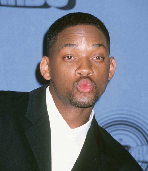 Will Smith macht ein Duckface vor einem blauen Hintergrund.