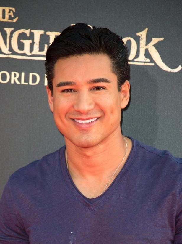 Mario Lopez lächelt vor einem „The Jungle Book“-Poster.
