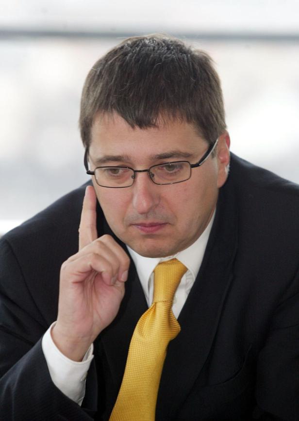 Ein Mann mit Brille und gelber Krawatte denkt nach.