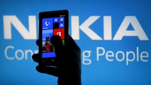 Eine Hand hält ein Nokia Smartphone mit Windows Phone Betriebssystem vor einem Nokia-Logo.