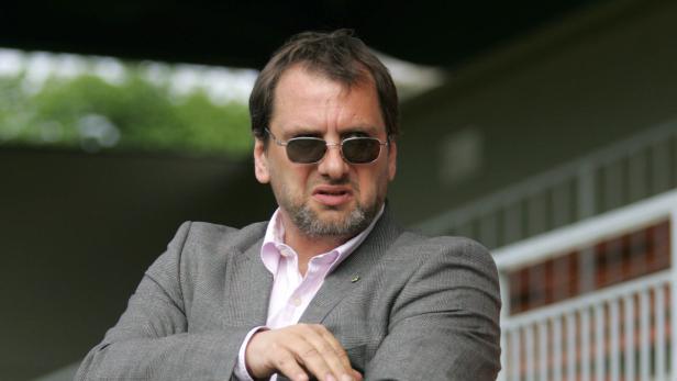 Ein Mann mit Sonnenbrille und grauem Sakko blickt in die Ferne.