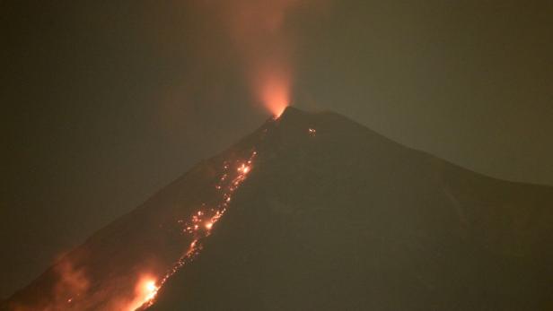 Ein Vulkan bricht aus und Lava fließt den Hang hinunter.