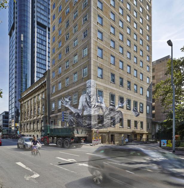 Ein Gebäude in Frankfurt mit einem großen Wandbild einer sitzenden Figur.