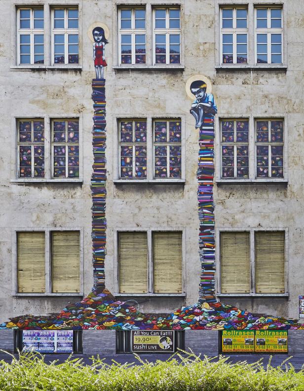 Ein Gebäude mit einem Wandgemälde von zwei Kindern, die auf Bücherstapeln stehen.