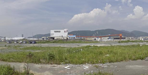 Eine Industrieanlage mit Kränen und Lagerhallen vor einer Hügelkette.