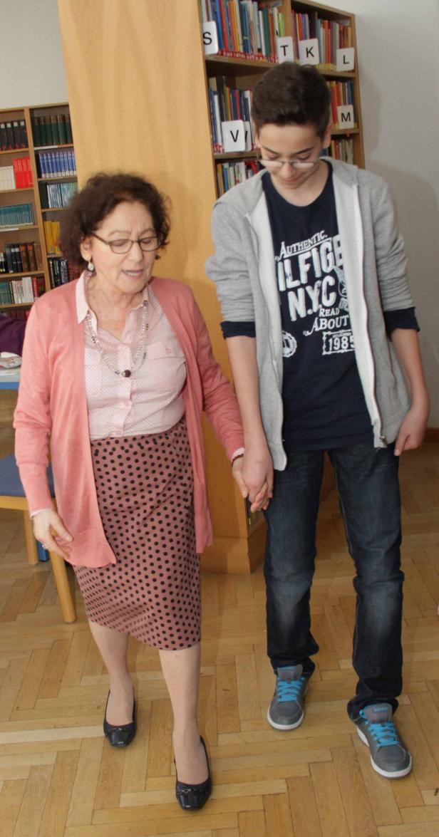 Eine ältere Frau hält die Hand eines Teenagers in einer Bibliothek.