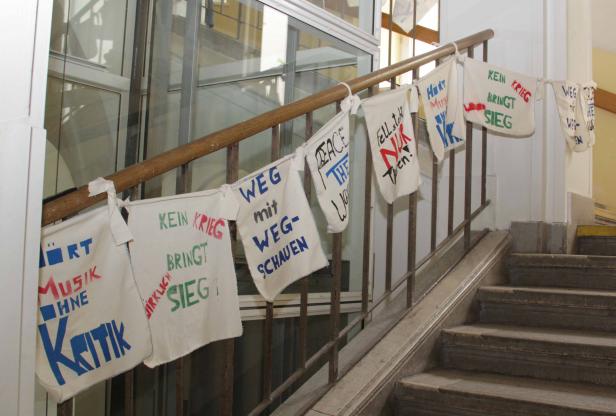 Auf einer Treppe hängen Stoffbanner mit Friedensbotschaften.