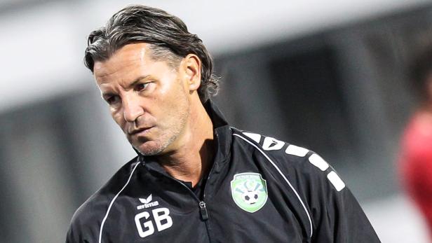 Ein Mann in einer schwarzen Jacke mit dem Logo des FC Pasching.