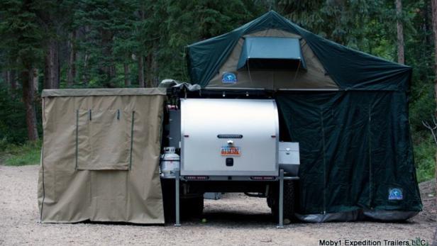 Ein Moby1 Expedition Anhänger mit Zeltaufbau steht im Wald.
