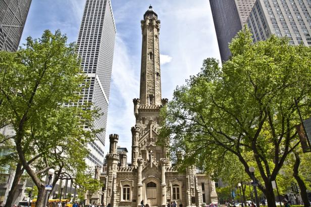 Der Chicagoer Wasserturm, ein historisches Gebäude, umgeben von Bäumen und Wolkenkratzern.