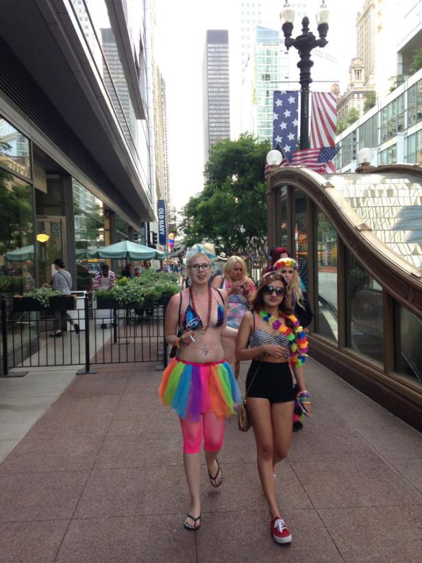 Mehrere Personen nehmen an einer Parade in farbenfrohen Kostümen in einer Stadt teil.