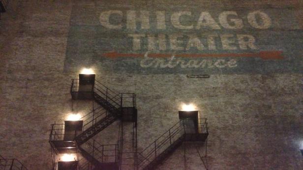Eine Backsteinmauer mit der Aufschrift „Chicago Theater Entrance“ und einer Treppe mit beleuchteten Absätzen.