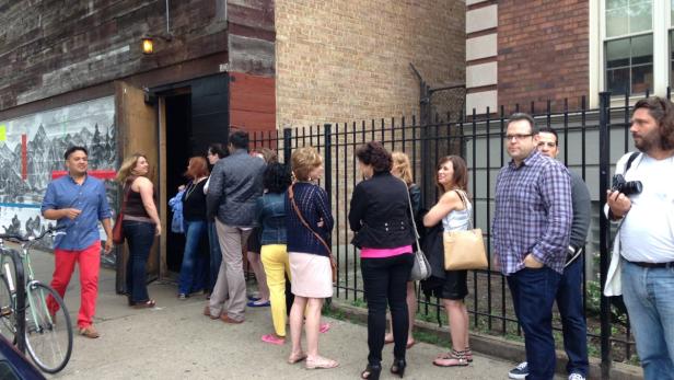 Eine Gruppe von Menschen wartet vor einem Gebäude.