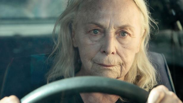 Eine ältere Frau mit blonden Haaren sitzt am Steuer eines Autos.