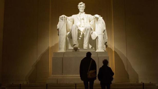 Zwei Personen betrachten die Statue von Abraham Lincoln im Lincoln Memorial in Washington, D.C..