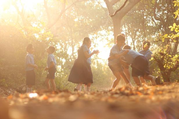 Eine Gruppe von Schulkindern spielt im goldenen Licht eines Parks.