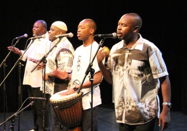 Eine Gruppe von Sängern und ein Trommler treten auf einer Bühne auf.