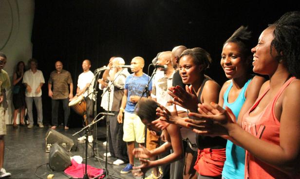 Eine Gruppe von Menschen steht auf einer Bühne und klatscht in die Hände.
