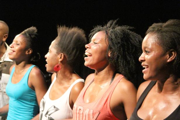 Eine Gruppe von Frauen singt gemeinsam auf einer Bühne.