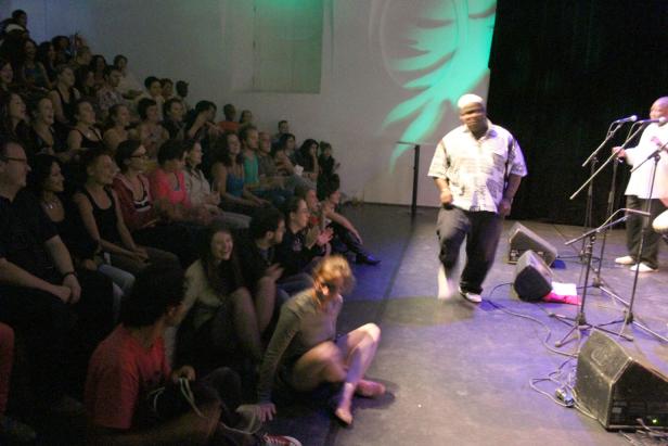 Ein Mann tanzt auf einer Bühne vor einem Publikum.