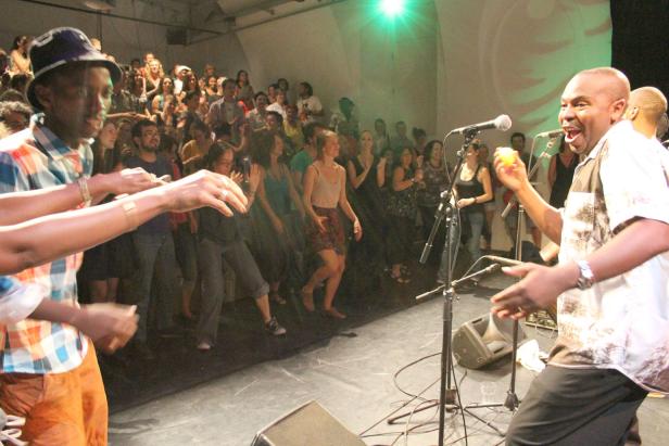 Ein Musiker spielt auf einer Bühne vor einem tanzenden Publikum.