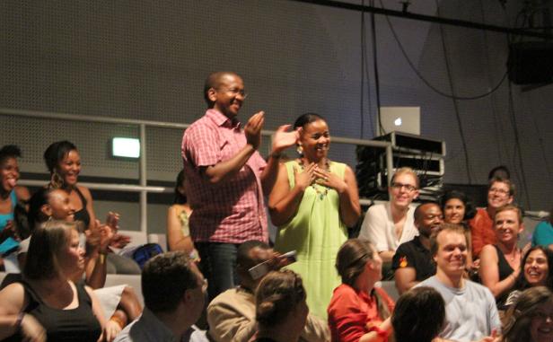 Ein Mann und eine Frau stehen vor einem Publikum und applaudieren.