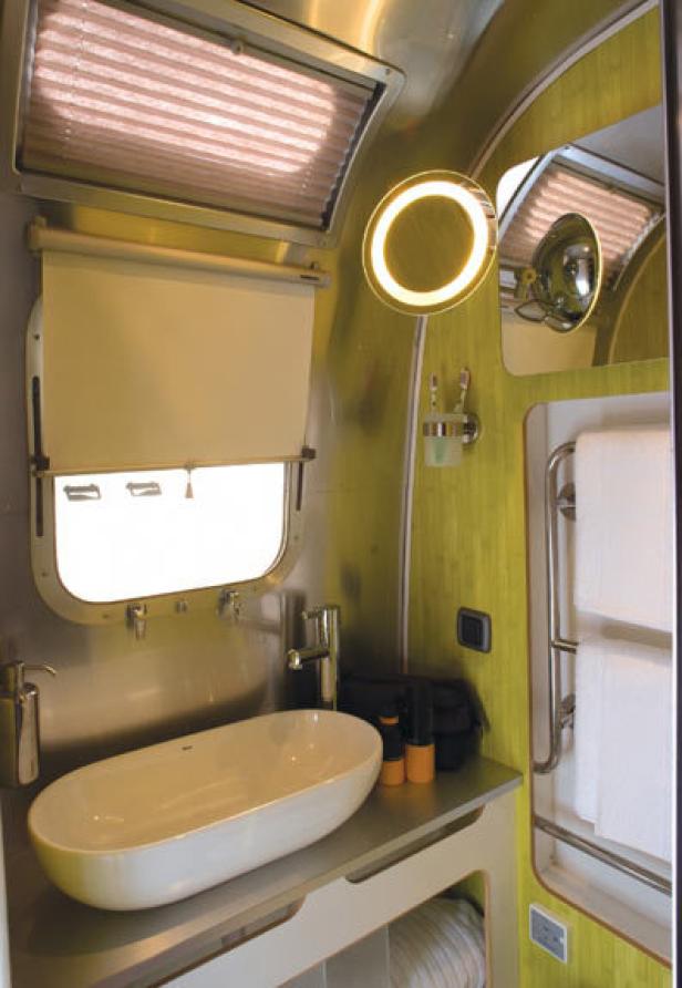 Das Badezimmer in einem Wohnwagen mit Waschbecken, Spiegel und Handtüchern.