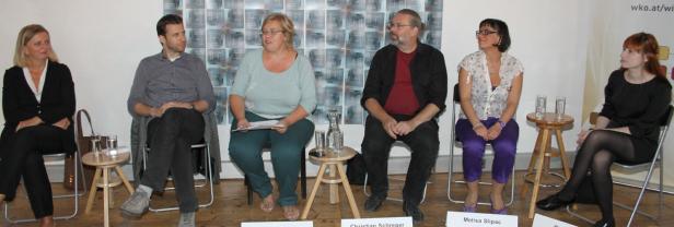 Sechs Personen sitzen bei einer Podiumsdiskussion auf Stühlen.