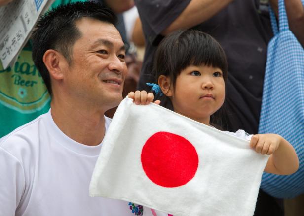 Ein Mann und ein kleines Mädchen halten eine japanische Flagge.