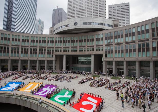 Eine Menschenmenge hält farbige Banner vor dem Tokyo Metropolitan Government Building.