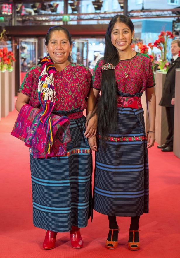 Zwei Frauen in traditioneller Maya-Kleidung stehen auf einem roten Teppich.