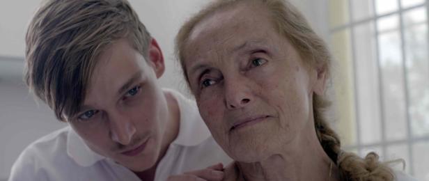 Ein junger Mann legt einer älteren Frau tröstend die Hand auf die Schulter.