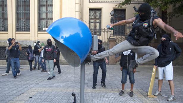 Eine Gruppe von Demonstranten, einige mit Masken, um eine blaue Telefonzelle.