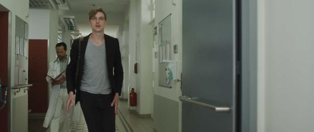 Ein Mann in einem Krankenhausflur geht an einem Arzt vorbei.