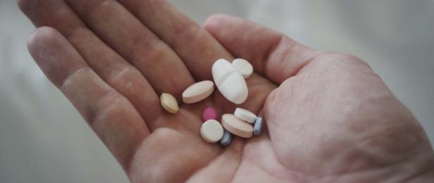 Eine Hand hält verschiedene Pillen in unterschiedlichen Farben und Formen.