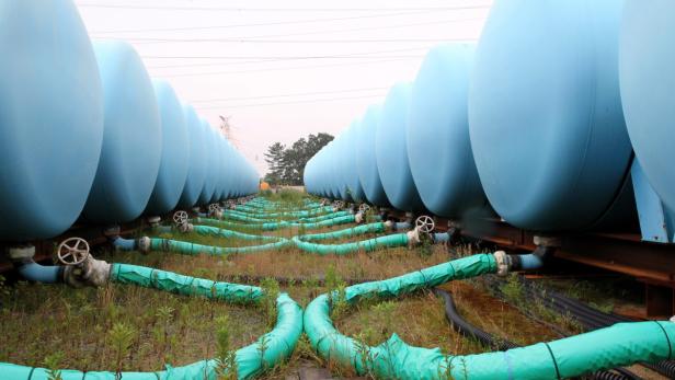 Tanks zum zwischenlagern Eine Reihe blauer Tanks mit grünen Rohren und Ventilen in einem Feld.