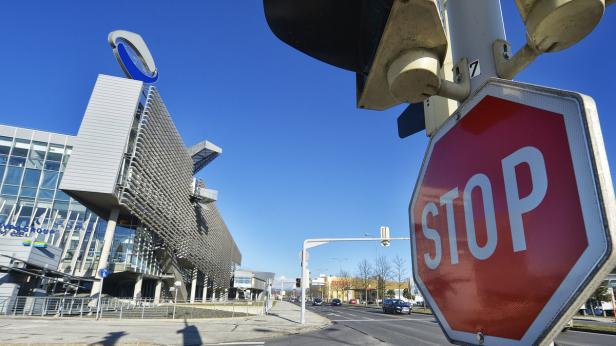 Ein Stoppschild steht an einer Straße vor einem modernen Gebäude unter blauem Himmel.