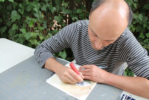 Ein Mann schneidet ein Bild mit einem Bastelmesser aus.